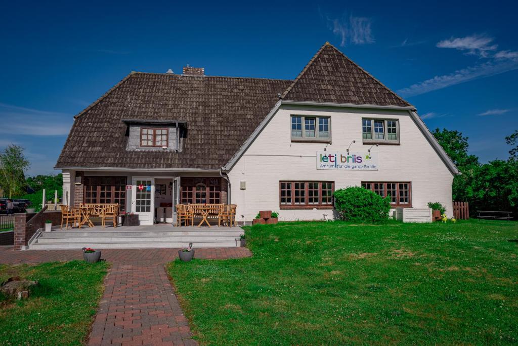 a white house with a table and chairs in the yard at Letj Briis in Norddorf