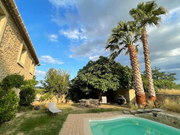 a house with a swimming pool and two palm trees at Chambres d&#39;hôtes la Soulenque Luxury B &amp; B in Capestang