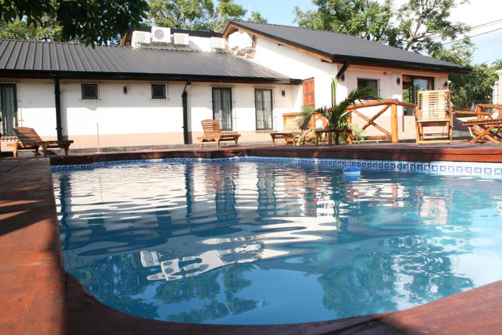 uma piscina com uma casa ao fundo em Posada del Jacarandá em Puerto Iguazú