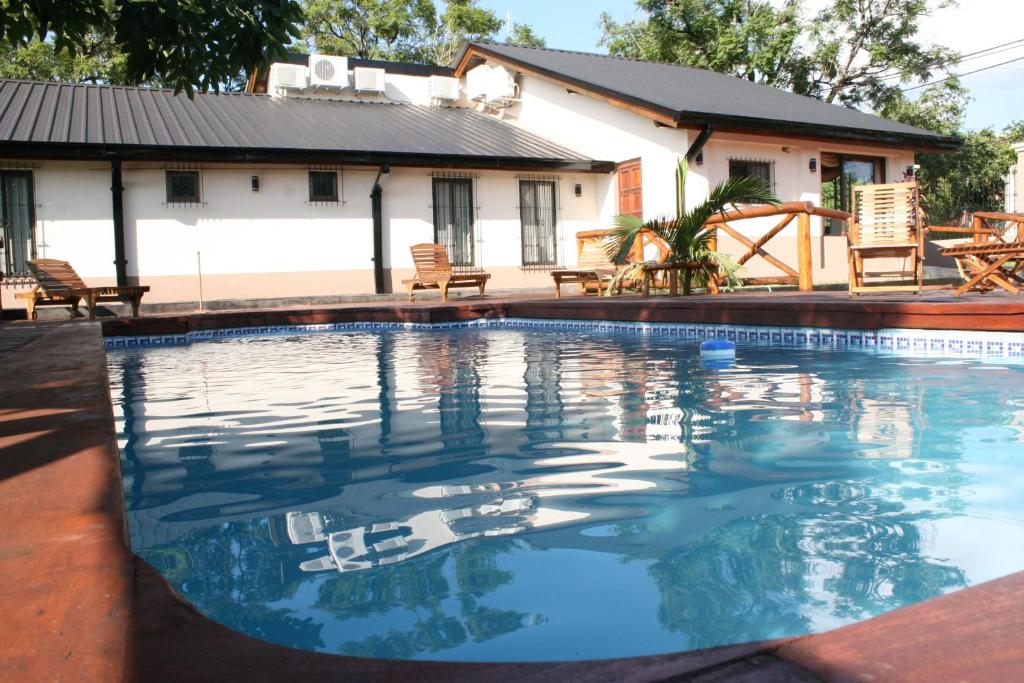 a swimming pool with a house in the background at Posada del Jacarandá in Puerto Iguazú