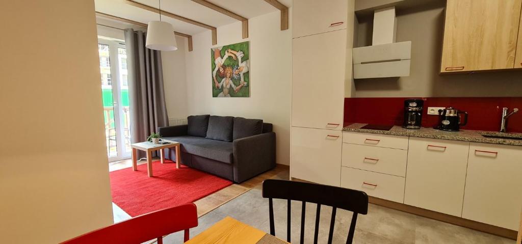 eine Küche und ein Wohnzimmer mit einem Sofa und einem Tisch in der Unterkunft Apartamenty EverySky - Źródlana 2 in Świeradów-Zdrój