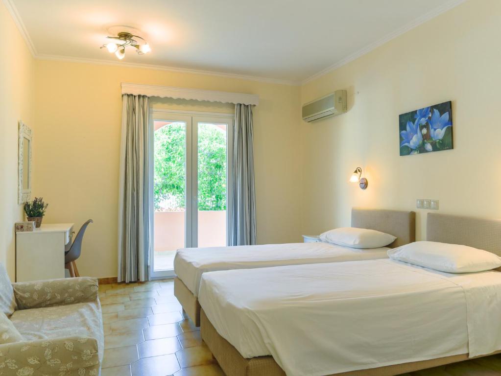 ein Hotelzimmer mit 2 Betten und einem Stuhl in der Unterkunft Fulvia Apartments in Kassiopi