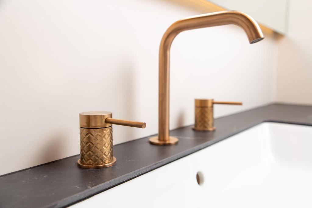 a kitchen sink with two copper faucets on it at Plaza Apartments in Opatija