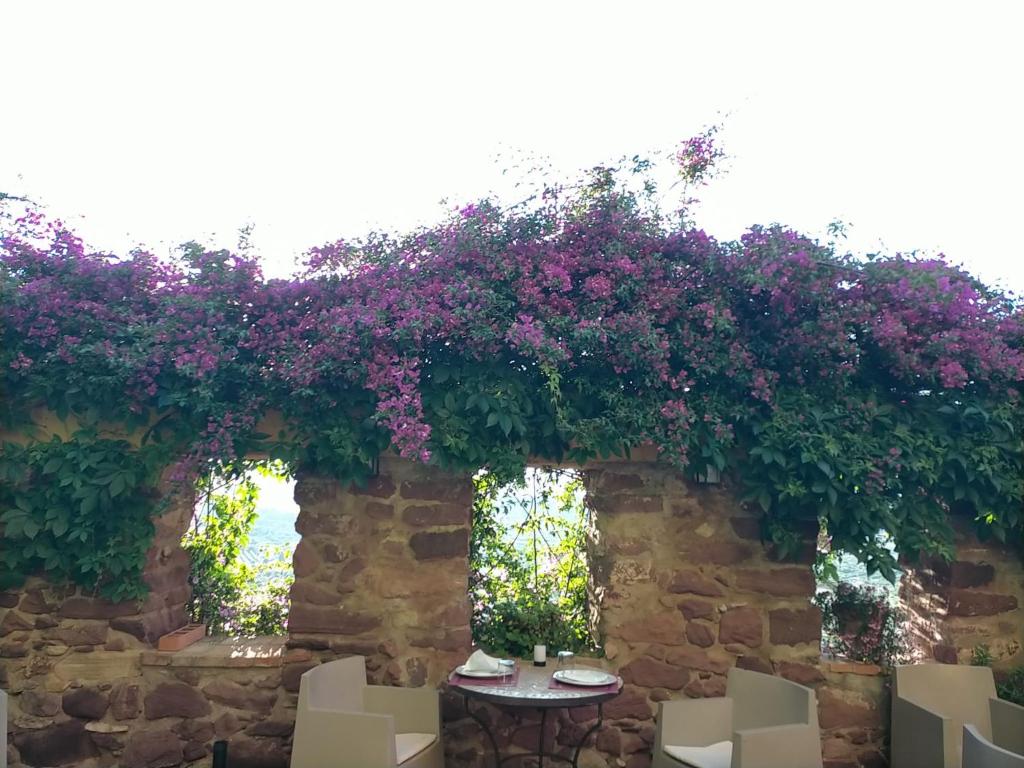 une table avec des fleurs violettes sur un mur en pierre dans l'établissement El Jardín Vertical, à Vilafamés