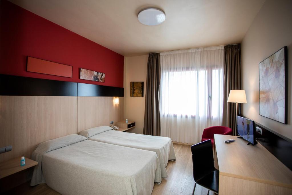 エヘア・デ・ロス・カバジェロスにあるHotel Ciudad De Ejeaのベッド2台とデスクが備わるホテルルームです。