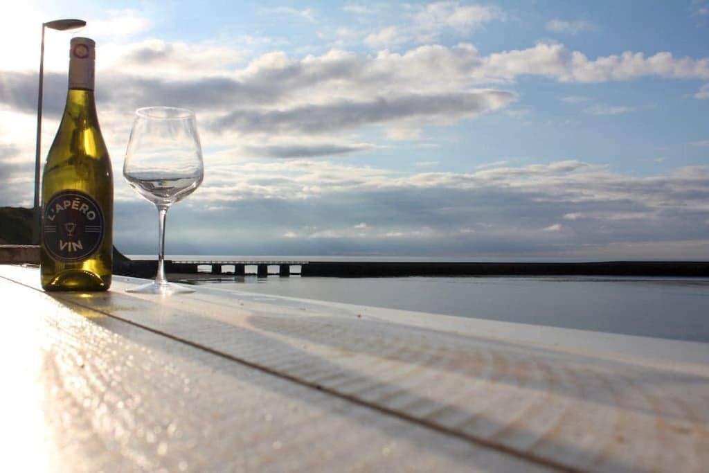 una bottiglia di vino e un bicchiere di vino su un tavolo di La Terrasse du Port - Front de Mer - 10 Personnes a Port-en-Bessin-Huppain