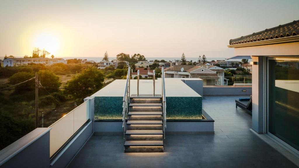 uma escada no telhado de uma casa com o pôr do sol em Balia Suites em Acharavi