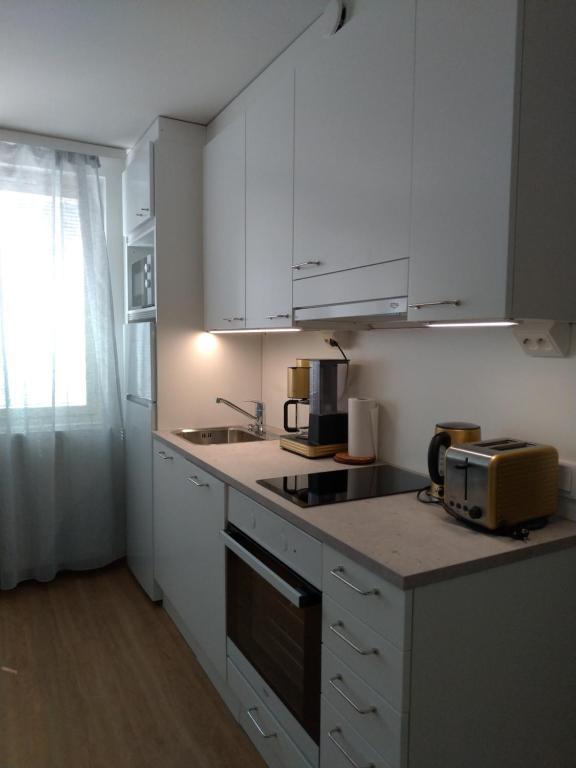 a kitchen with white cabinets and a counter top at Apartments Käyräkatu in Jyväskylä
