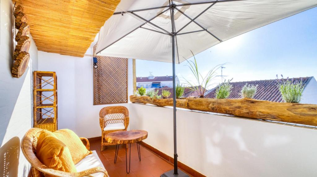 格蘭杜拉的住宿－Villa Center - Alojamento Local，阳台配有遮阳伞、椅子和桌子。