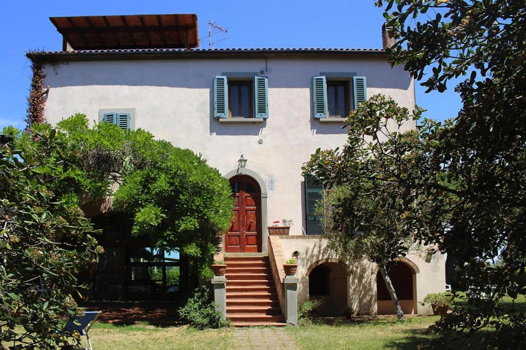 una casa con una puerta roja y algunos árboles en Holiday resort Azienda Canova Seconda Marina di Grosseto - ITO03010-CYB en Marina di Grosseto