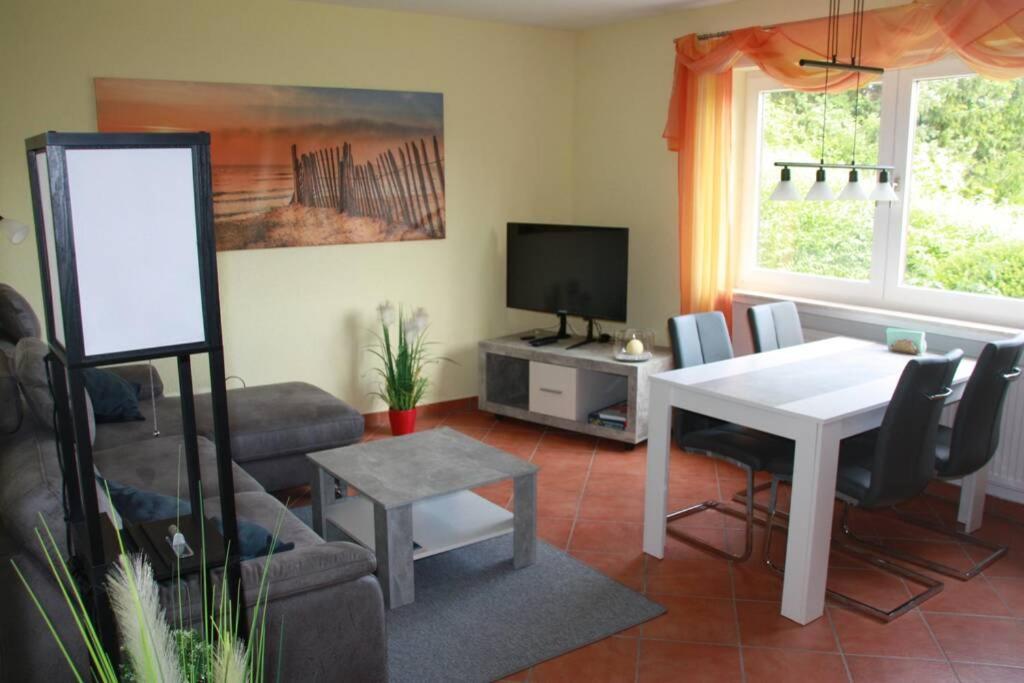 a living room with a white table and a tv at Ferienwohnung Solmsbachtalblick in Braunfels