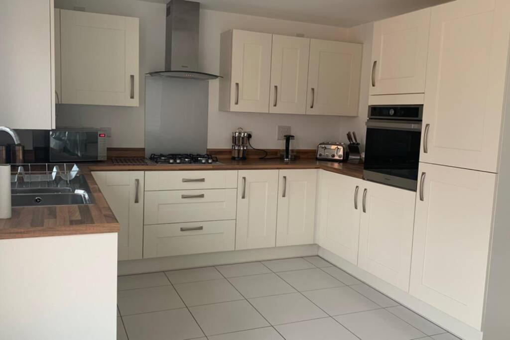 uma cozinha com armários brancos e um forno com placa de fogão em Stanton Cross 5 persons 3 Bed Home em Wellingborough