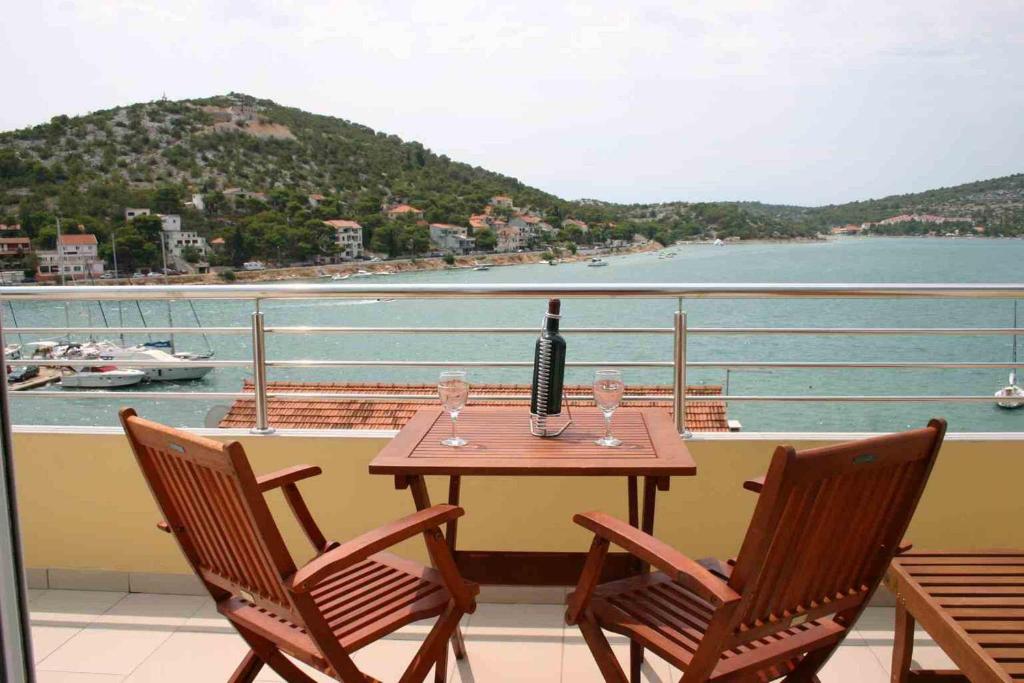 a table with a bottle of wine and glasses on a balcony at Villa Stegic in Tisno