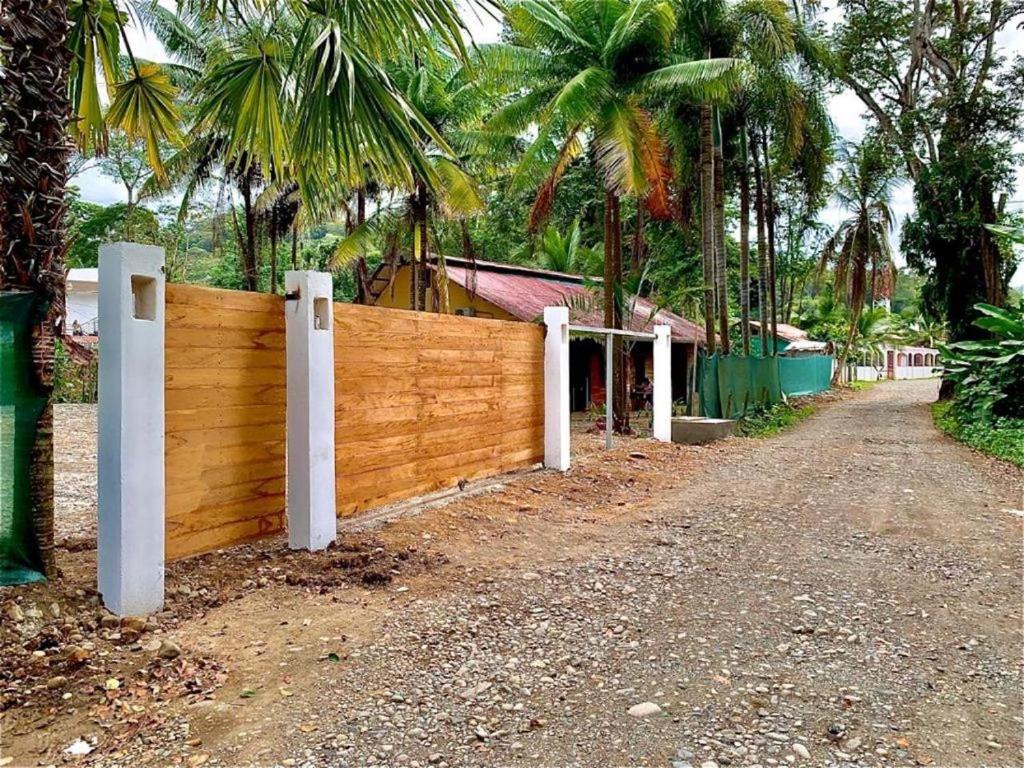 a wooden fence in front of a house with palm trees at Casa Nara in Puerto Viejo