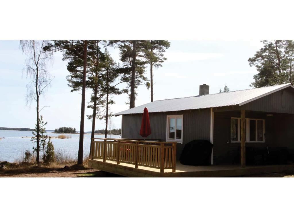 a small house with a deck next to a lake at Svinö Seaside Villa in Lumparland