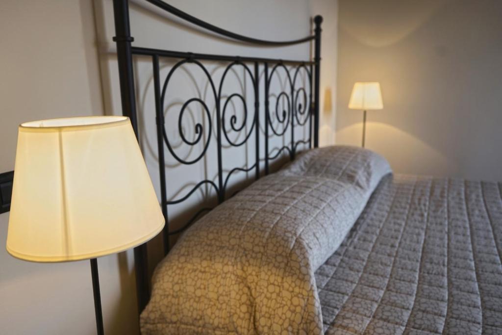 a bedroom with a bed with a black headboard and a lamp at Locanda OSTERIA LA MILONGA in Agliano Terme