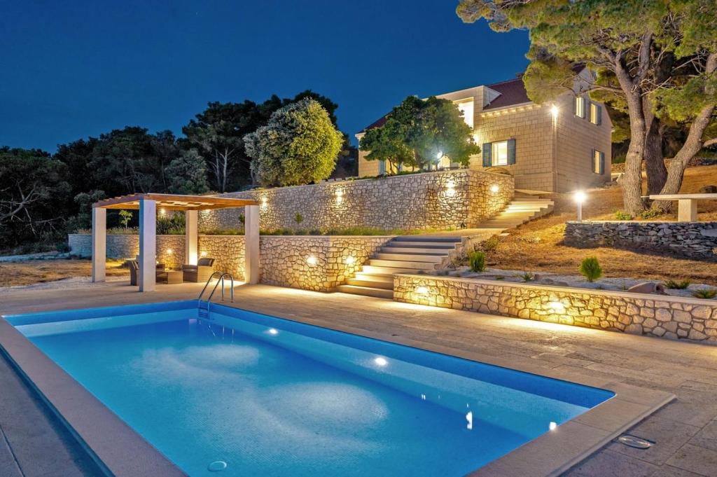 een zwembad in de achtertuin van een huis 's nachts bij Luxury Villa Castello di Pietra with private pool in Pučišća