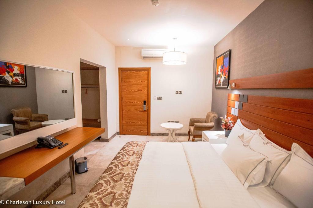 ポートハーコートにあるCharleson Luxury Hotelのベッドとリビングルームが備わるホテルルームです。