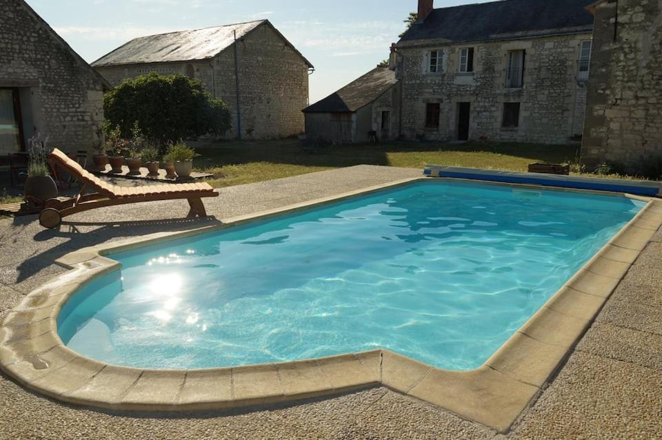 une grande piscine bleue avec un banc en face d'une maison dans l'établissement VALINIERE VILLAGE maison détente TENNIS ET PISCINE, à Champigny-sur-Veude