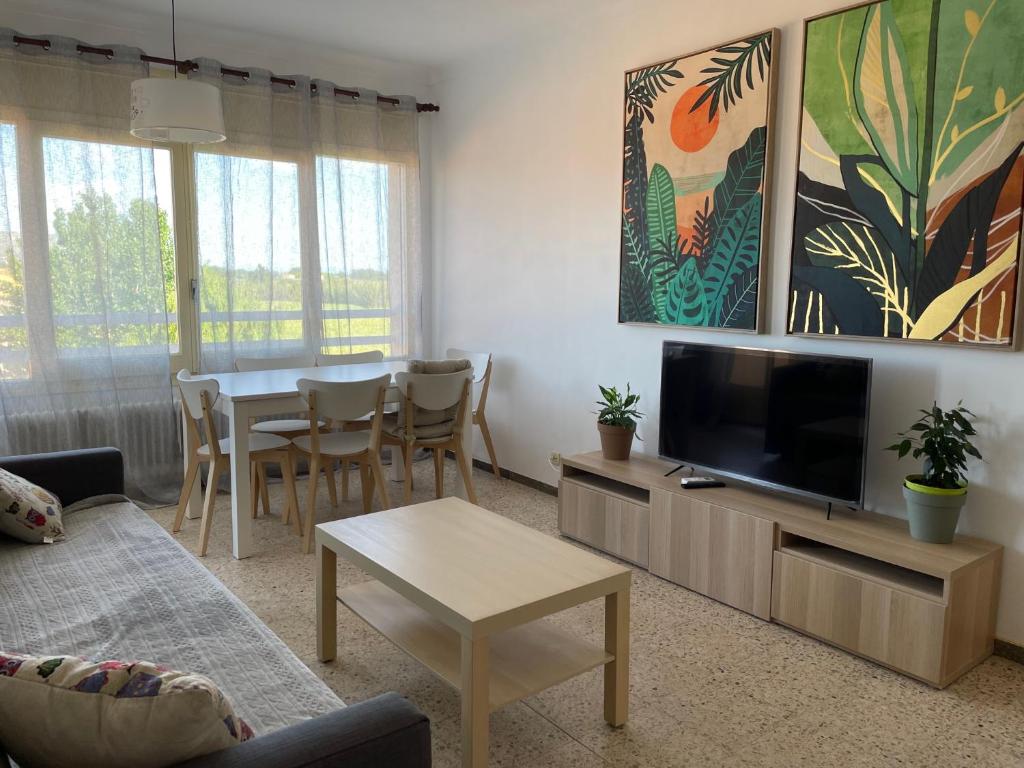 een woonkamer met een televisie en een tafel met stoelen bij Apartment Costa Brava en Verges in Verges