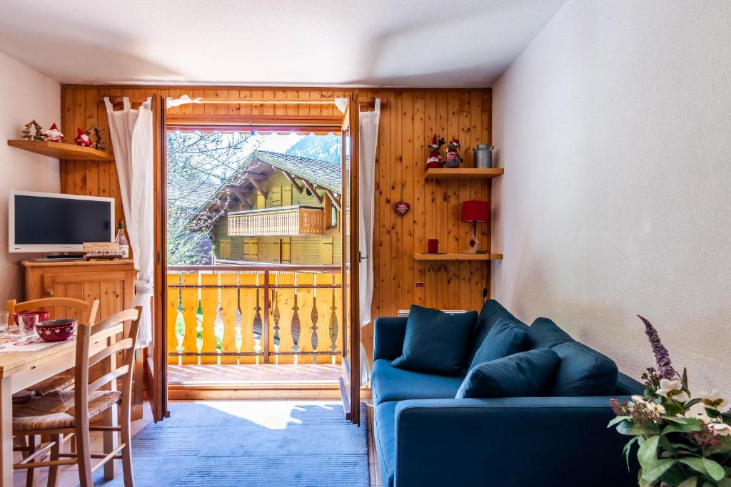un salon avec un canapé bleu devant une fenêtre dans l'établissement OREE DES PISTES 18, à Morzine