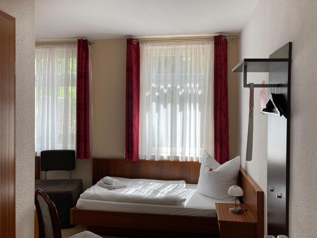 Pension am Theater في فايمار: غرفة نوم بسرير ونافذة ذات ستائر حمراء