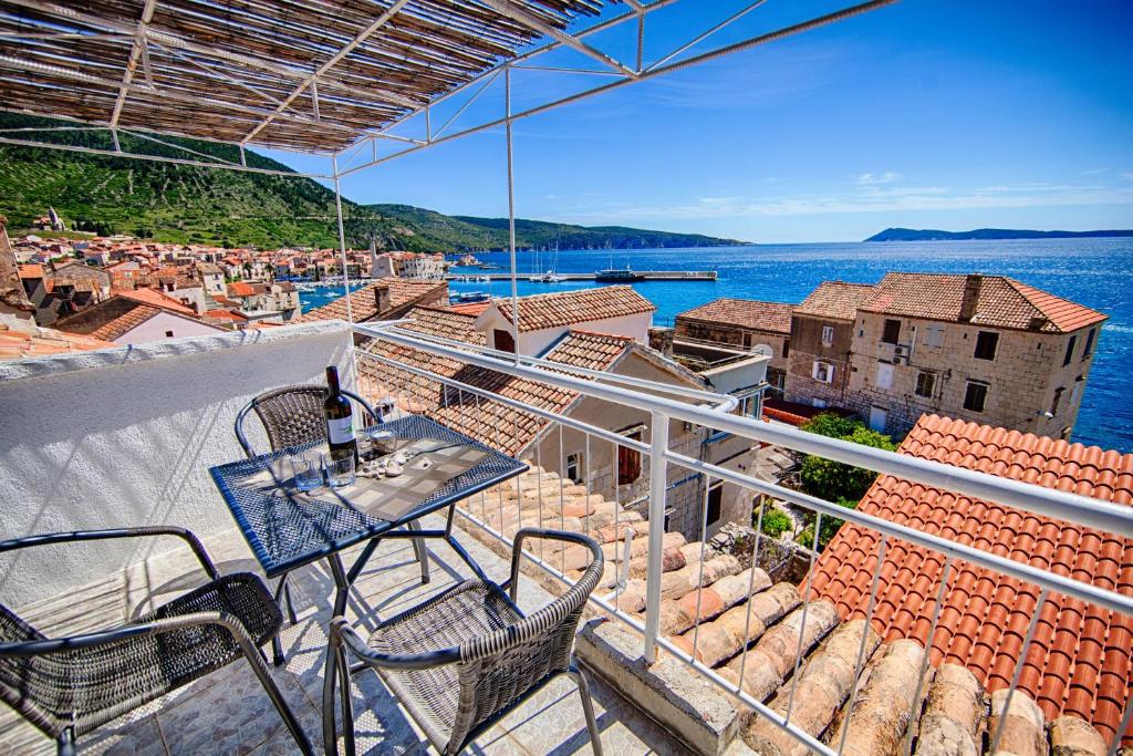 a balcony with a table and chairs and the water at Komiza Provita Guesthouse in Komiža