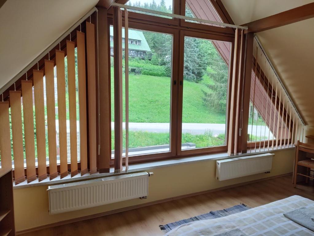 a bedroom with a large window with a view of a yard at Třílůžkový pokoj Pension Kubů in Špindlerův Mlýn