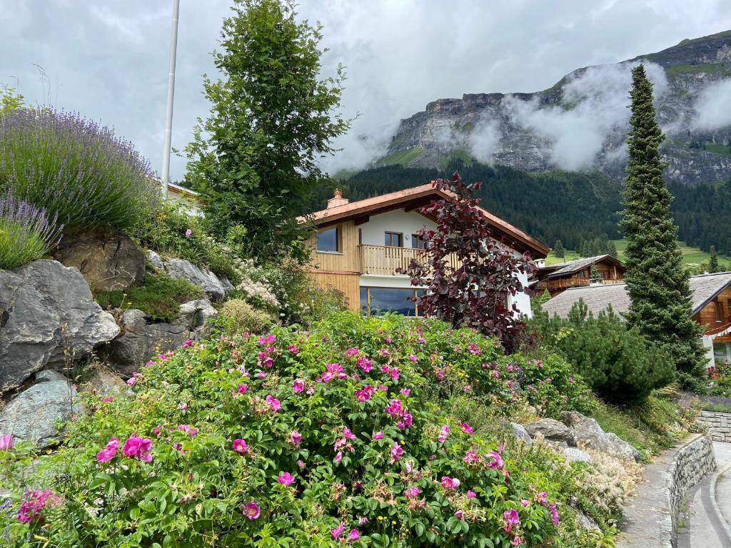 a house with flowers in front of a mountain at El Cantun - 7 Zimmer Einfamilienhaus mit 200m2 in Flims