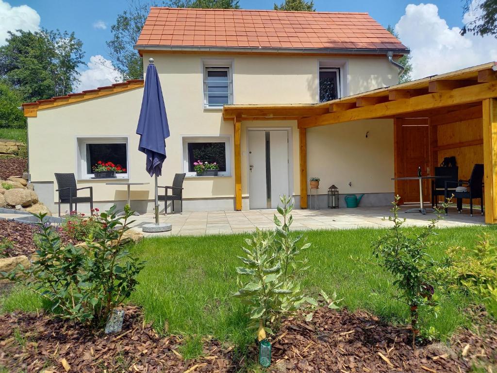 ein Haus mit einer Terrasse und einem Sonnenschirm in der Unterkunft Ferienhaus Richtermühle in Sebnitz