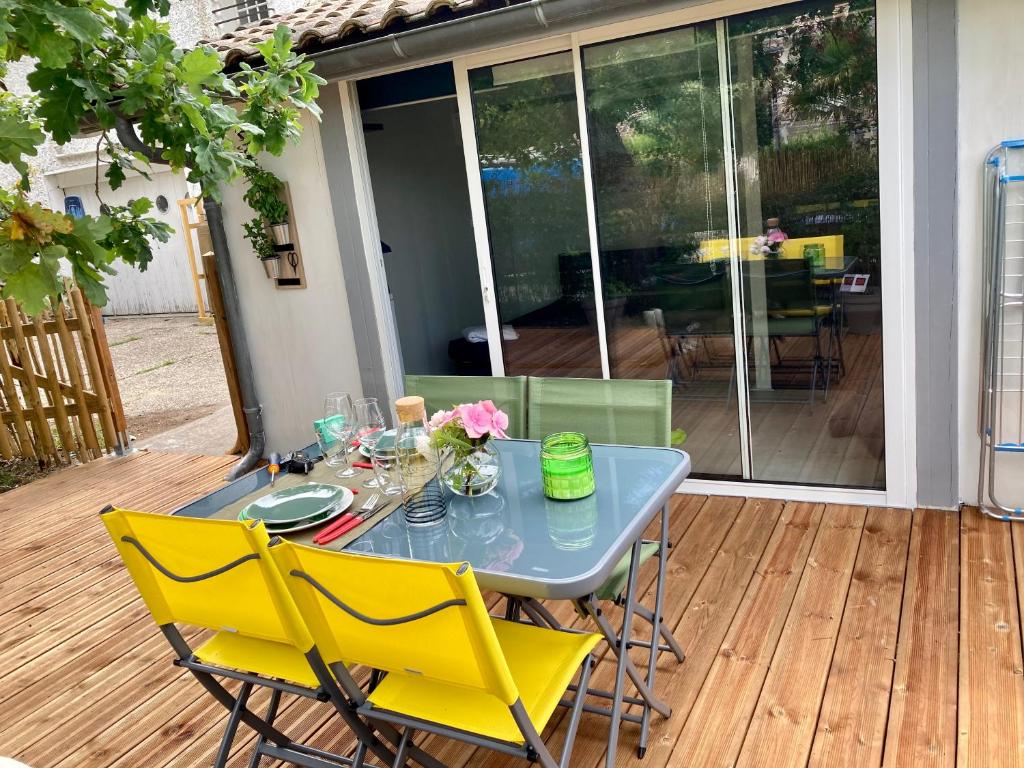 een tafel en stoelen op een terras met een tafel en gele stoelen bij Charmant chalet avec une grande terrasse au Pyla in La Teste-de-Buch