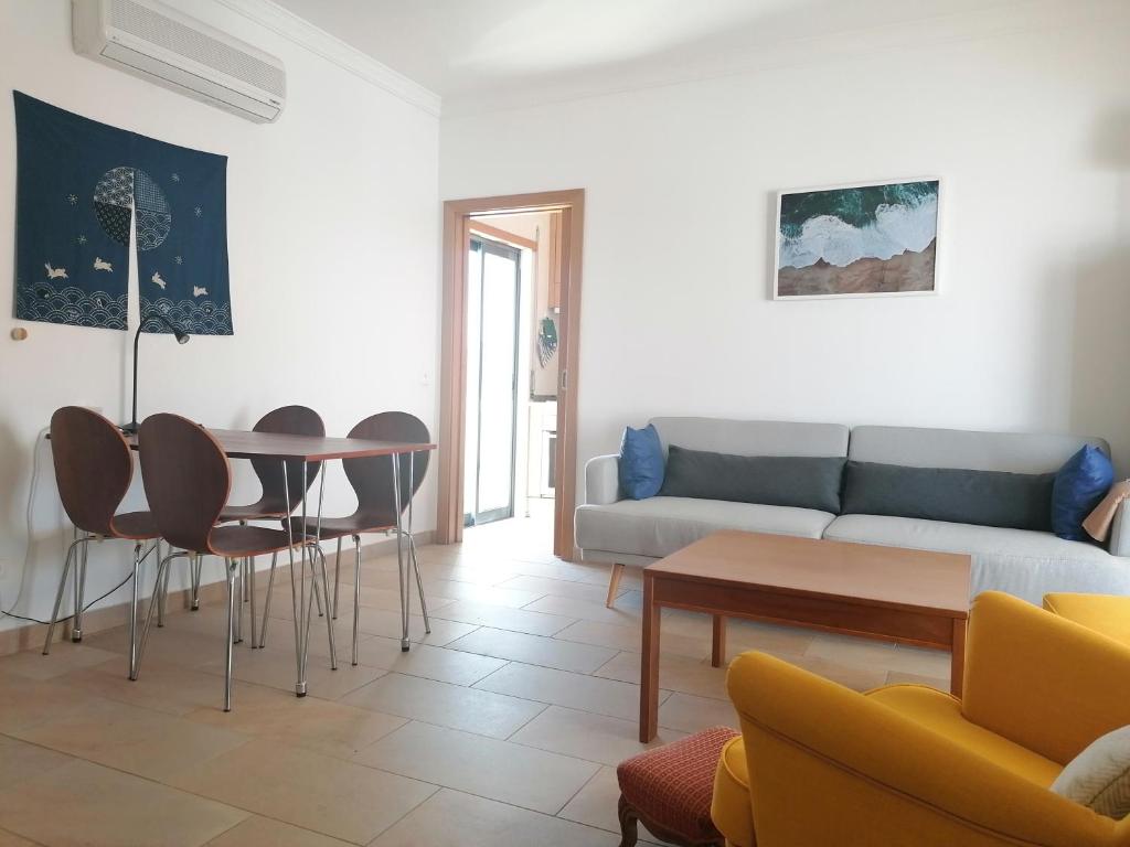 un soggiorno con un divano, un tavolo e delle sedie di Cabanas Riverside a Cabanas de Tavira