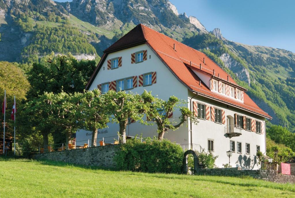 uma casa branca com um telhado vermelho numa colina em Hotel Restaurant Schlössli Sax em Sax