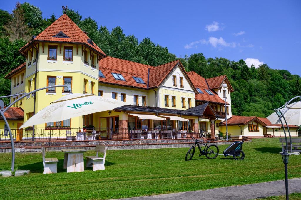 ein großes gelbes Haus mit einem Regenschirm davor in der Unterkunft Hotel Julianin dvor in Habovka