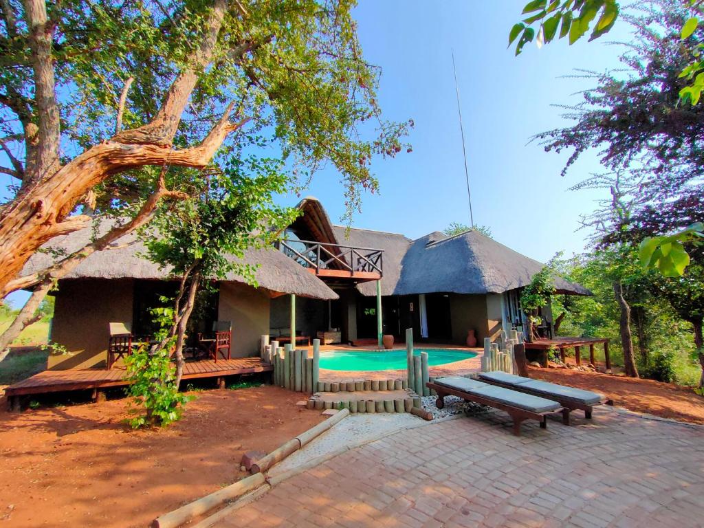 a house with a thatched roof and a swimming pool at Lions Place in Grietjie Game Reserve