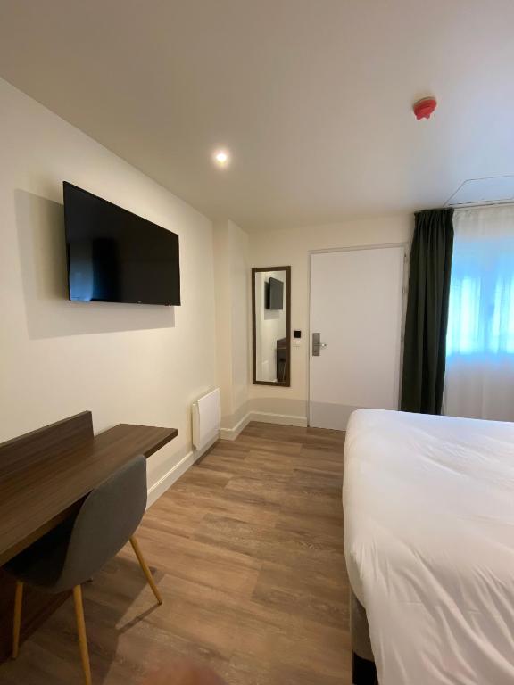 Cette chambre comprend un lit, un bureau et une télévision. dans l&#39;établissement Mayrena Hotel Restaurant - Destination Le Tréport Mers, à Eu