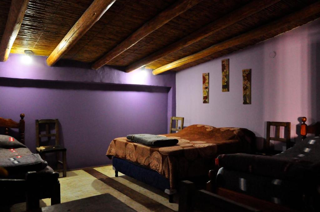 una camera con due letti e pareti viola di Giramundo Hostel Purmamarca a Purmamarca