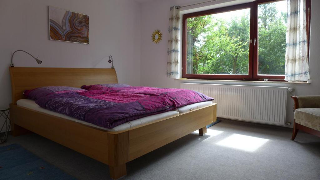 a bedroom with a bed with a purple comforter and a window at Gemütliches Zimmer mit Doppelbett und Tischtennisraum in Tuchenbach