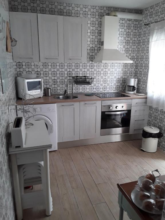 Una cocina con gabinetes blancos, un fregadero y un microondas. en Anahouse, en Alcalá de Henares