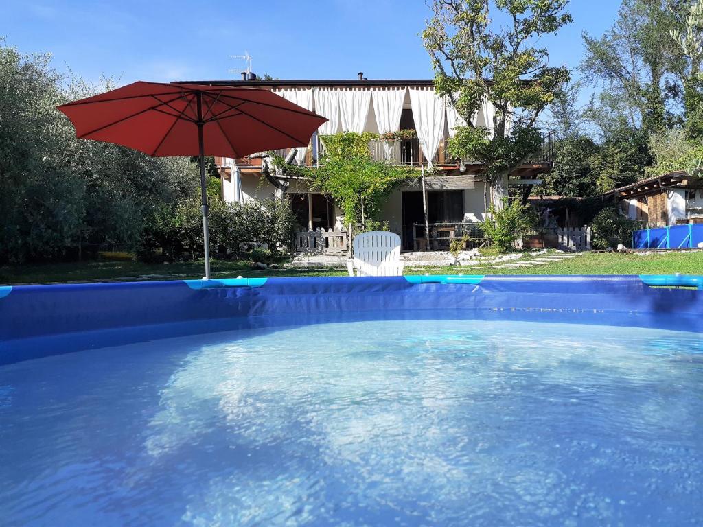 a red umbrella sitting in a swimming pool at La Casa di Paglia in San Felice del Benaco