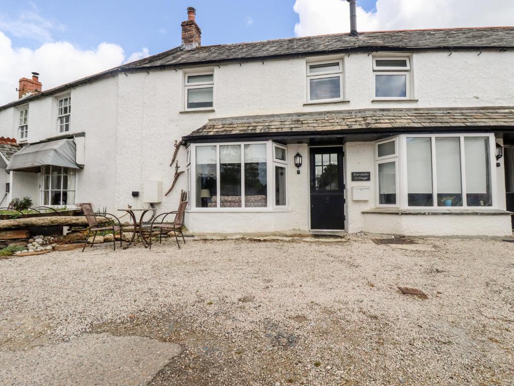 a white house with a table and chairs in front of it at Kerslake Cottage in Bodmin