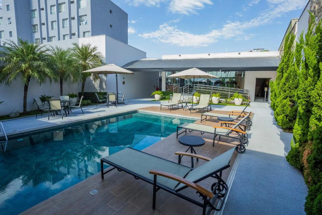 a swimming pool with tables and chairs next to a building at Hotel Florença in Americana