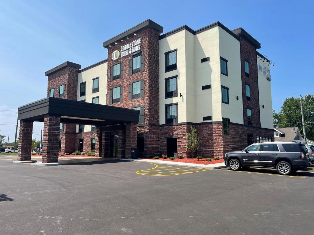 a car parked in a parking lot in front of a building at Cobblestone Hotel & Suites - Little Chute in Little Chute