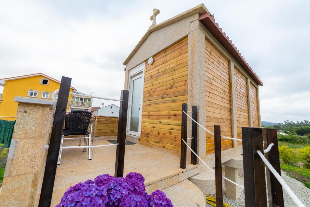 a small wooden house with a balcony with purple flowers at El horreo in Mazaricos