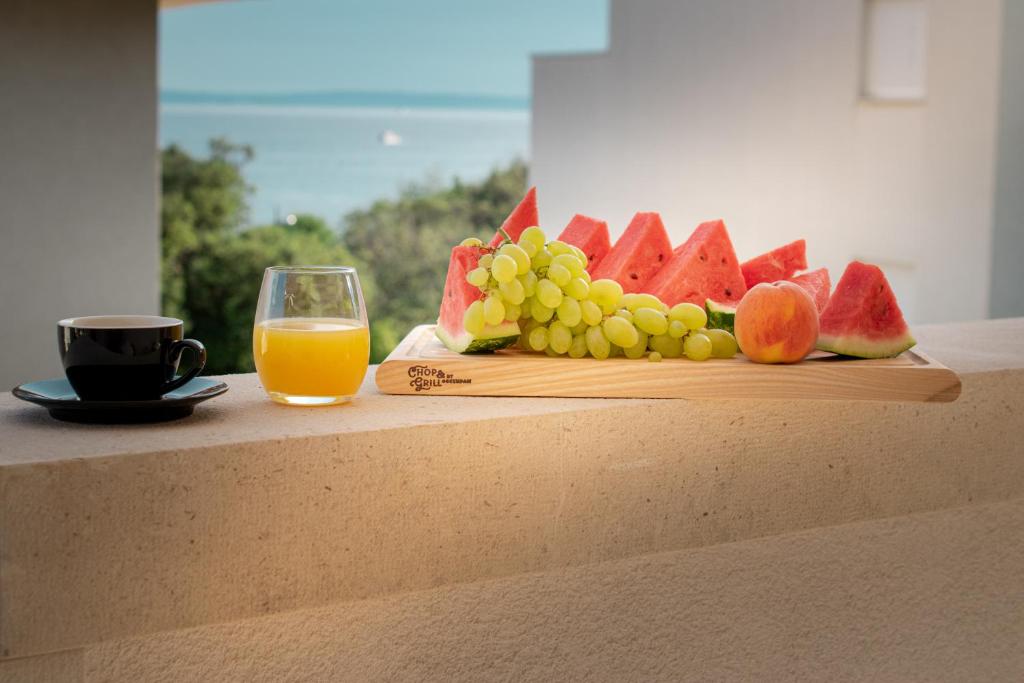 ein Schneidebrett mit Obst und ein Glas Orangensaft in der Unterkunft Luxury apartment Mirage Split in Split