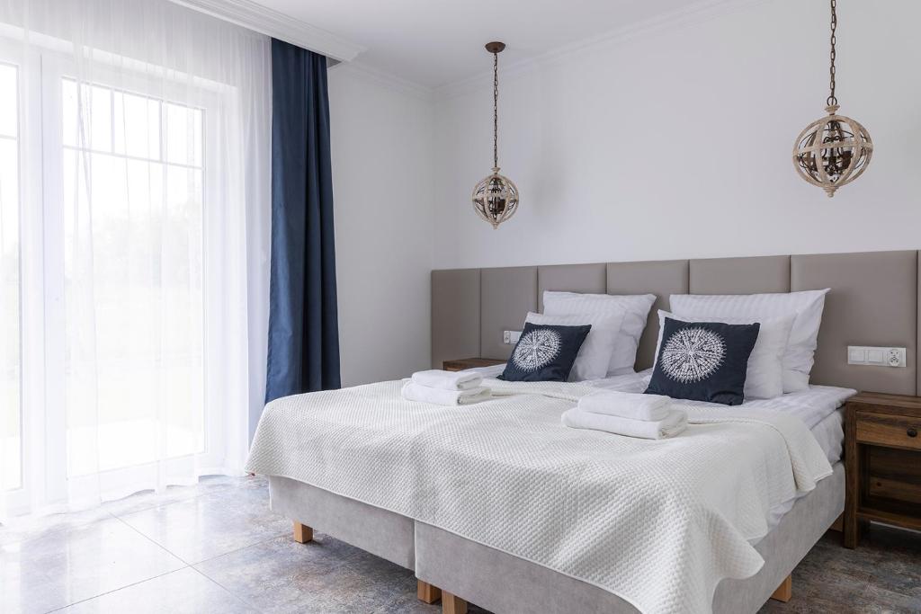 a white bedroom with a large bed with two pillows at Gościnny Dom Nad Morzem in Mielenko