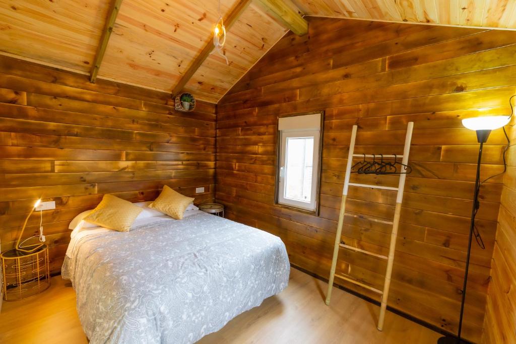 Un dormitorio con una cama en una cabaña de madera. en LA CABAÑA Del Camino, en Mazaricos