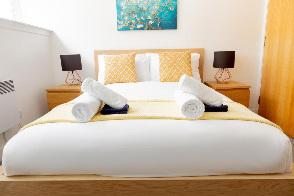 a bedroom with a large white bed with towels on it at Modern Merchant City Apartment by George Square in Glasgow