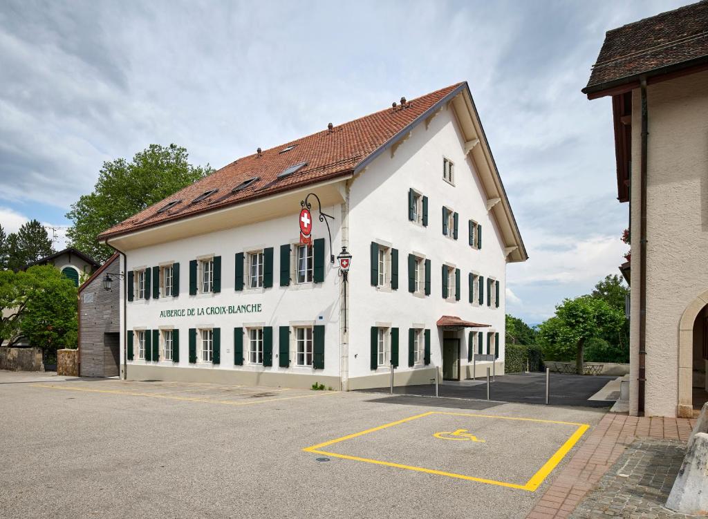 un gran edificio blanco con un letrero rojo. en Auberge La Croix-Blanche en Gingins