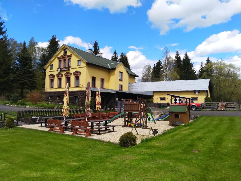 a yellow building with a playground in front of it at Penzion Karolína in Lučany nad Nisou
